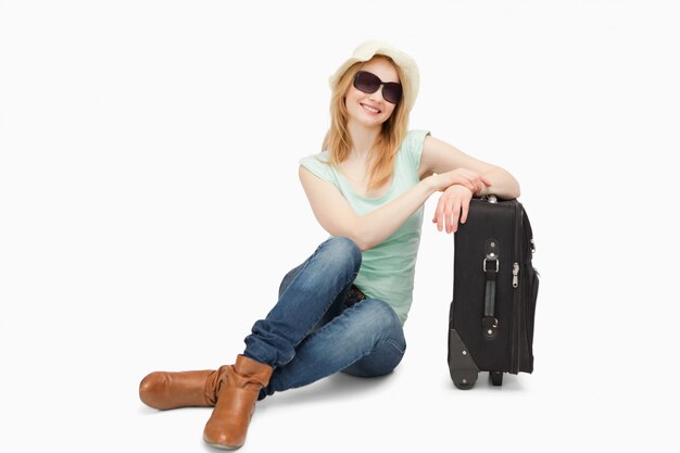 Woman sitting next to a suitcase