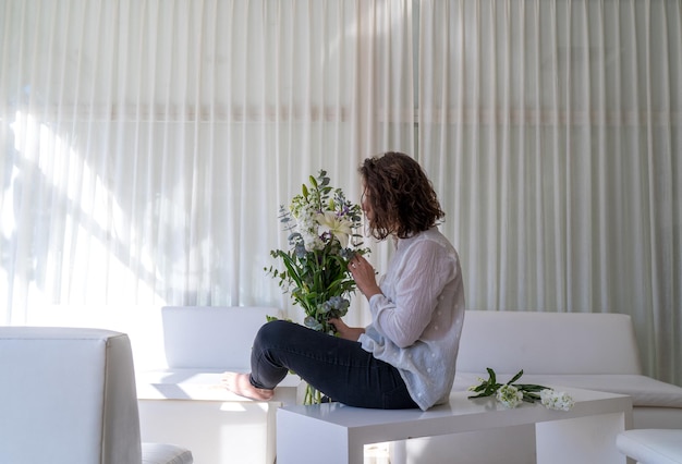 Woman sitting on table by potted plant