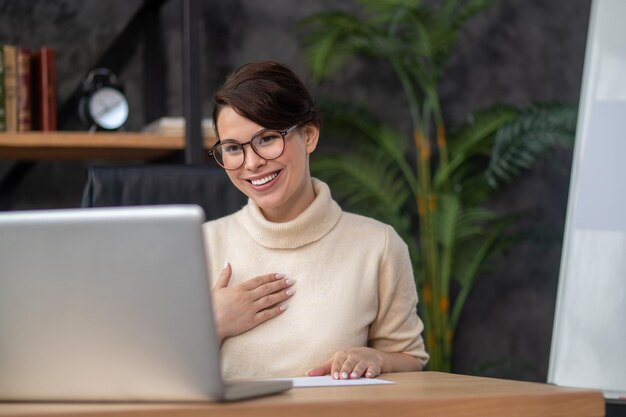 A woman sitting at the table and having a video call