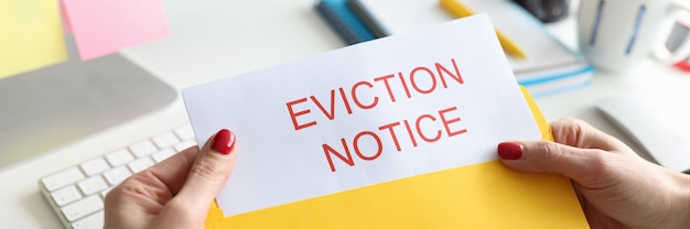 Woman sitting at table and holding eviction letter closeup