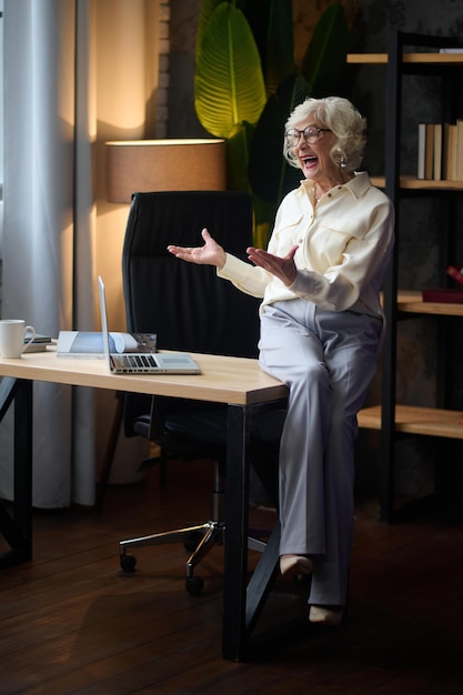 Woman sitting on table near laptop talking