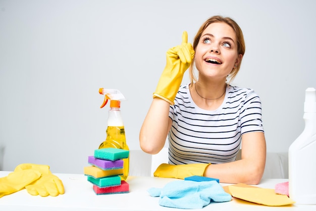 Woman sitting at the table rubber gloves cleaning housework detergent service High quality photo