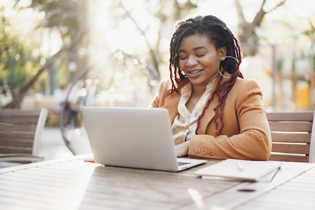 woman sitting at the table in street cafe and using laptop