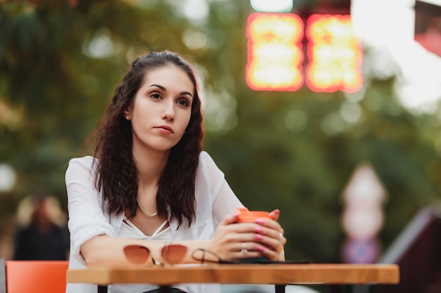 Woman sitting at a table on the street. Evening warm city. High quality photo