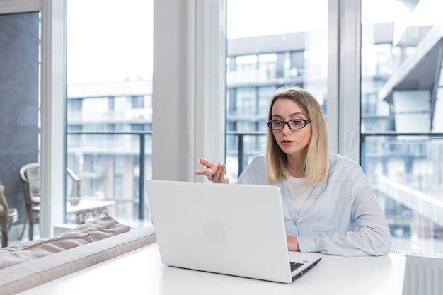 woman sitting at table and talking online on webcam remotely