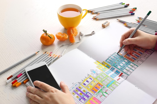 Woman sitting at table with coloring book for adults closeup