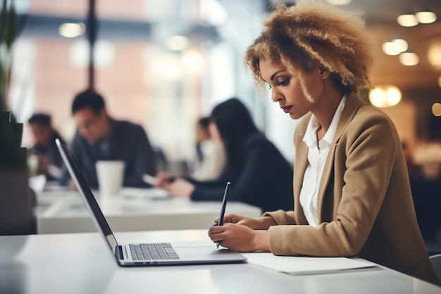 Photo a woman sitting at a table with a laptop and pen