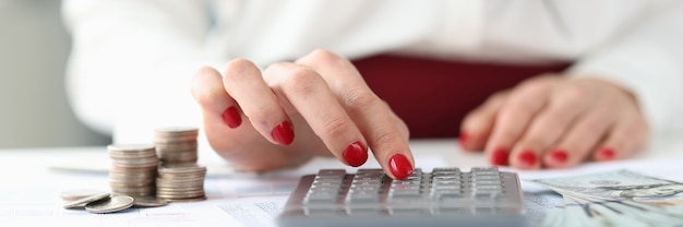 Woman sitting at table with money and counting on calculator concept successful business and