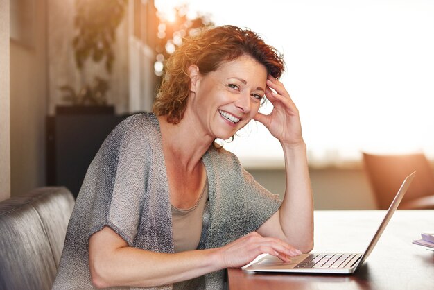 Woman sitting at table with smiling  with laptop
