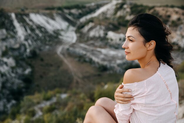 Photo woman sitting on a top of a mountain enjoying landscapes.