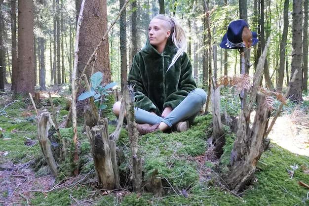 Foto donna seduta sul tronco di un albero nella foresta