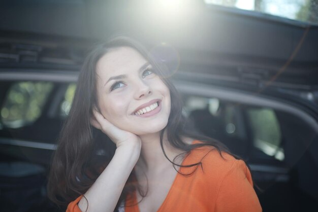 若い美しい春の車のトランクに座っている女性