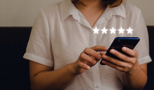 Woman sitting using smartphone and giving a five-star symbol to boost business concept score. with experience in customer service