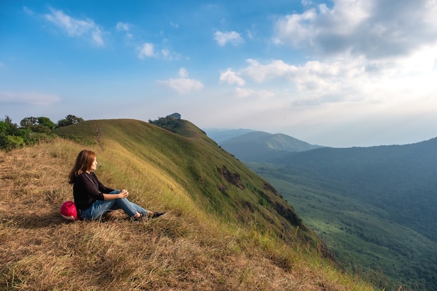 座って夕方に山の景色と夕日を見ている女性