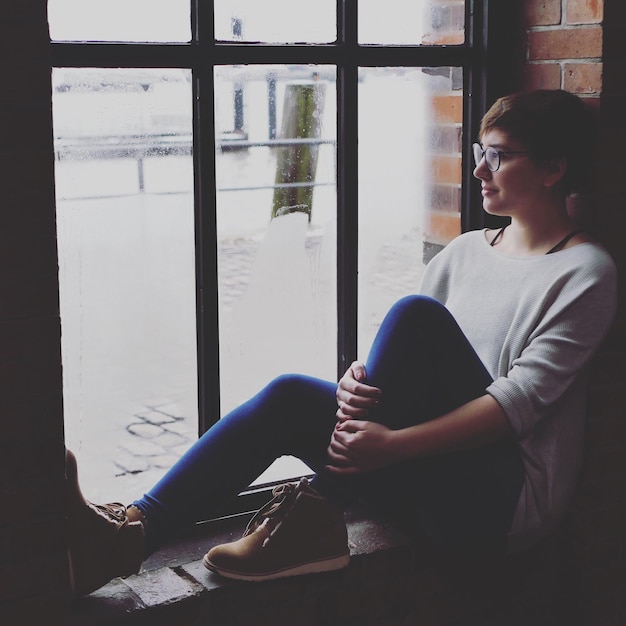 Photo woman sitting in window sill