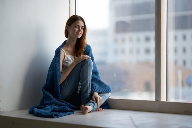 Woman sitting on the windowsill with a blue plaid dreamy look