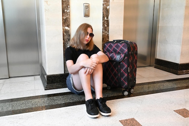 Photo a woman sitting with a feeling of sadness and loss while traveling with a lot of luggage on the floor the room is occupied