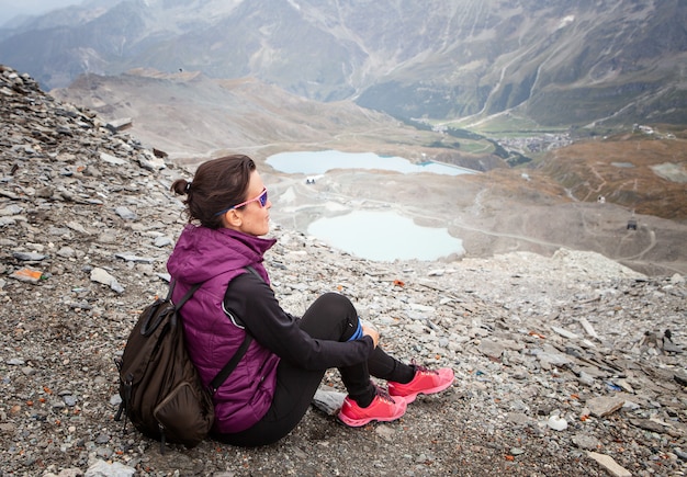 Woman sitting with her backpack looking at the landscape