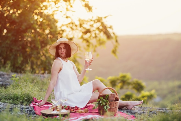 Woman sitting with sweets and wine at nature