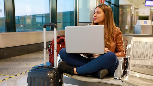 A woman sitting and working on laptop at the airport