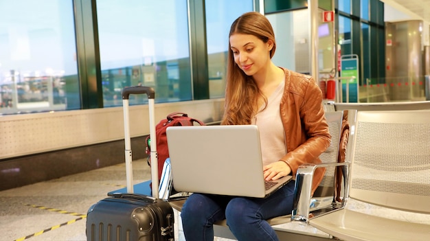 A woman sitting and working on laptop at the airport