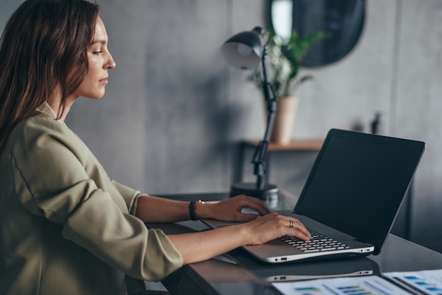 Woman sitting and working at workplace with laptop