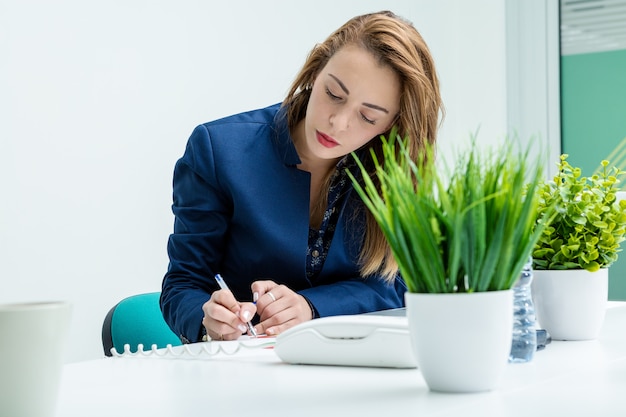 Woman sitting and writing in office