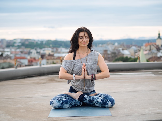 Woman sitting on yoga mat with closed eyes while meditating