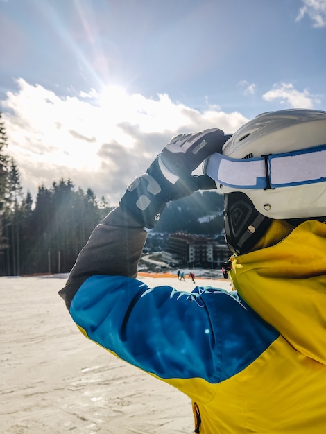 Woman in ski goggles looking at sun winter resort\
activities