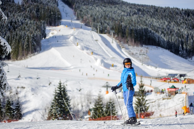 Woman skier against ski slopes and ski-lift on background