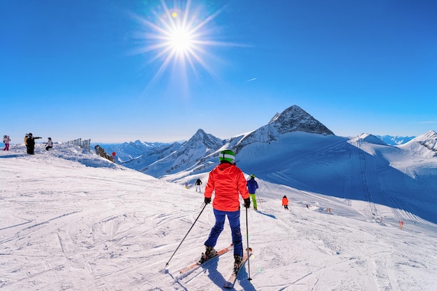 Woman Skier skiing at Hintertux Glacier in Tyrol, Mayrhofen in Austria, winter Alps. Lady girl Ski at Hintertuxer Gletscher in Alpine mountains with white snow and blue sky. Sun shining.