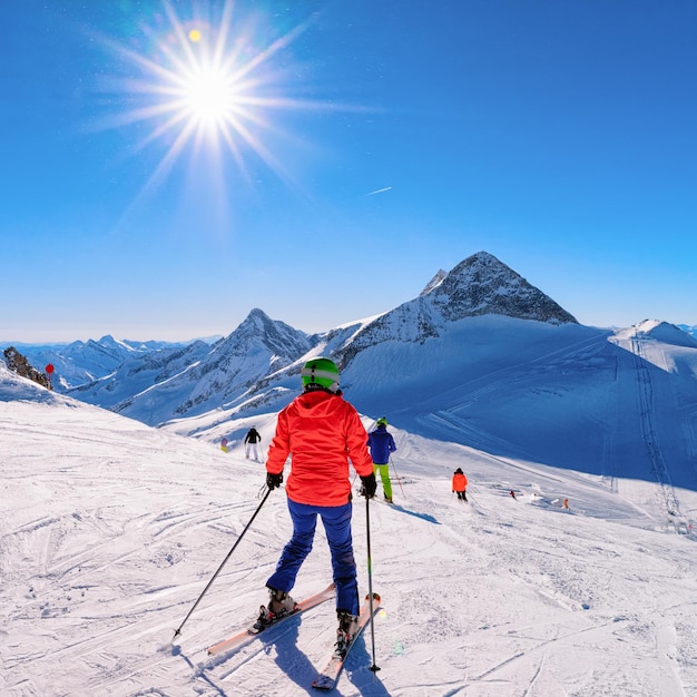 オーストリアのマイヤーホーフェン、冬のアルプスのチロルのヒンタートゥクス氷河でスキーをする女性スキーヤー。白い雪と青い空とアルプスの山々にあるHintertuxerGletscherでの女性の女の子のスキー。太陽が輝いています。