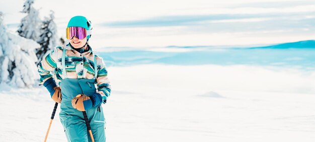 Foto donna in abbigliamento da sci con casco e occhiali da sci in testa con bastoncini da sci tempo invernale sulle piste in cima a una montagna e vista panoramica sciatore alpino sport invernali