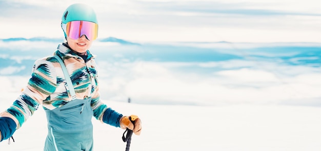 Foto donna in abbigliamento da sci con casco e occhiali da sci in testa con bastoncini da sci tempo invernale sulle piste in cima a una montagna e vista panoramica sciatore alpino sport invernali