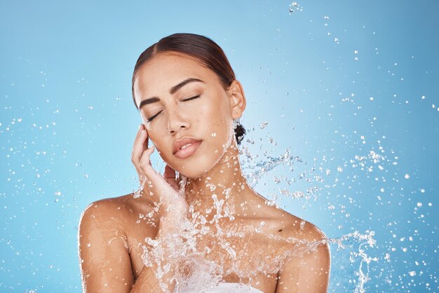 Woman skincare hand or water splash face on blue background studio in healthcare wellness brazil hygiene maintenance or bathroom grooming beauty model shower or wet water drop for facial cleaning