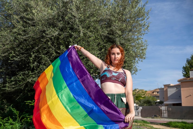 A woman in a skirt holding a colorful kite near a small building