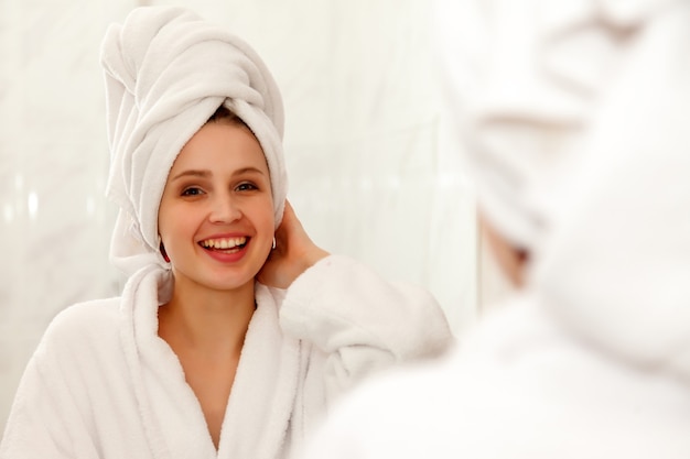 Woman of Slavic appearance in dressing gown smiles in mirror