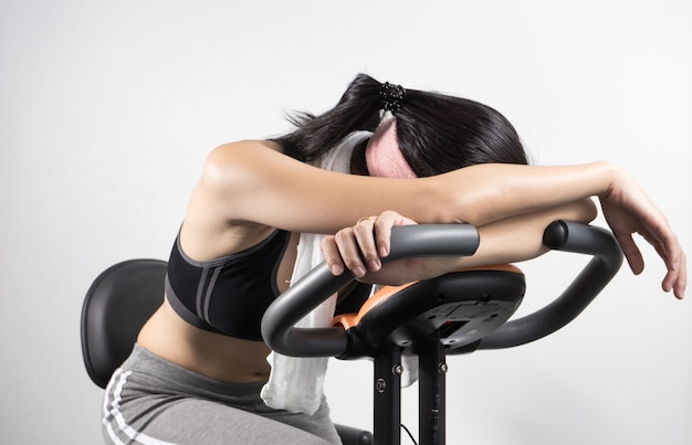 Woman sleep on exercise bike over white background