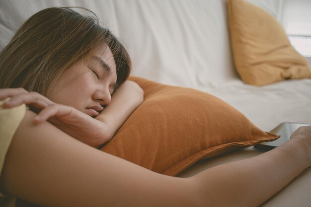 Woman sleep on the sofa with the mobile phone still on her hand