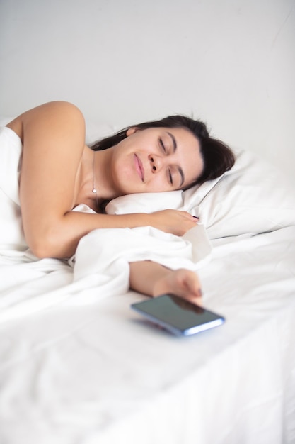 Woman sleeping in bed phone in her hand