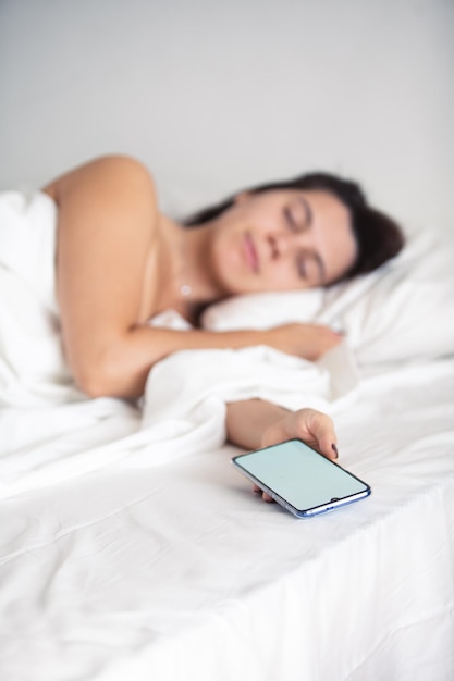 Woman sleeping in bed phone in her hand