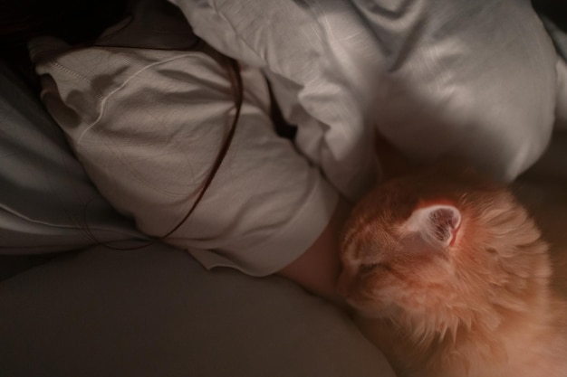 Foto donna che dorme a letto con il suo gatto proprietario con il suo animale notturno