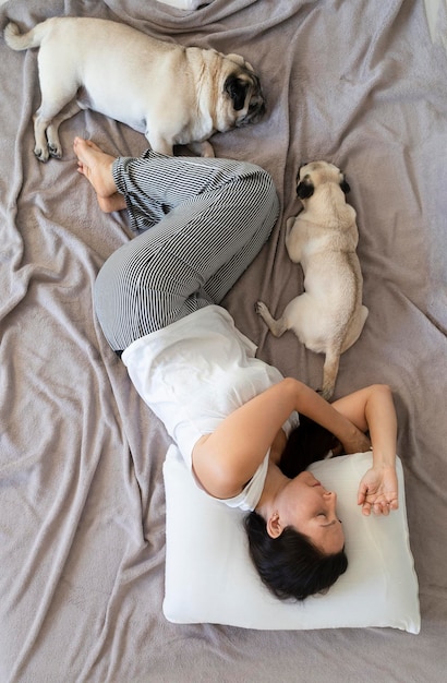 Woman sleeping in bed with her two pug dogs