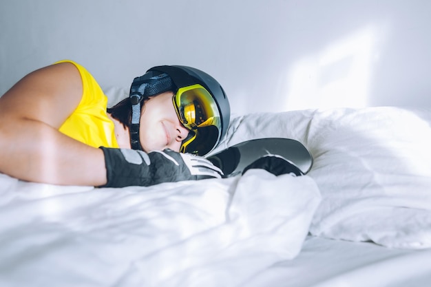 Woman sleeping in bed with snowboard dreaming about ski at snow mountains