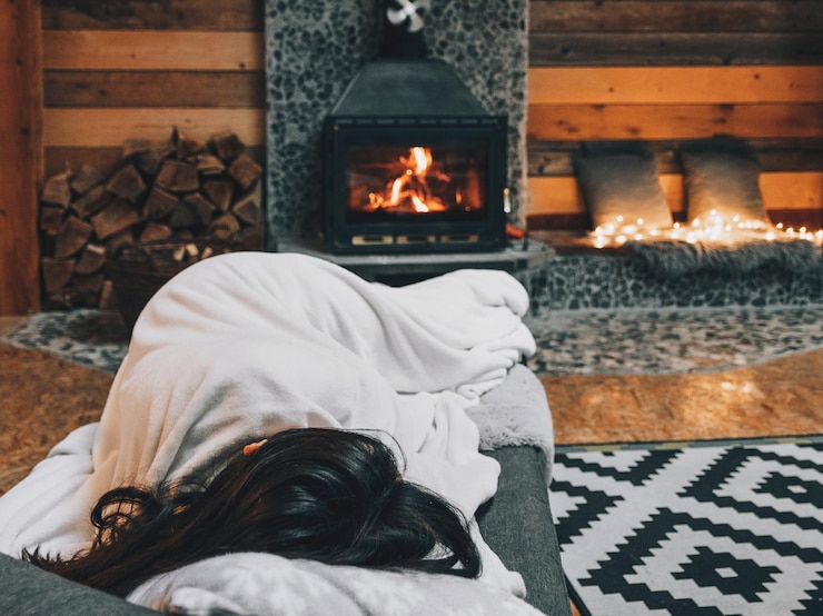 Photo woman sleeping on couch by fireplace in cozy warm cabin