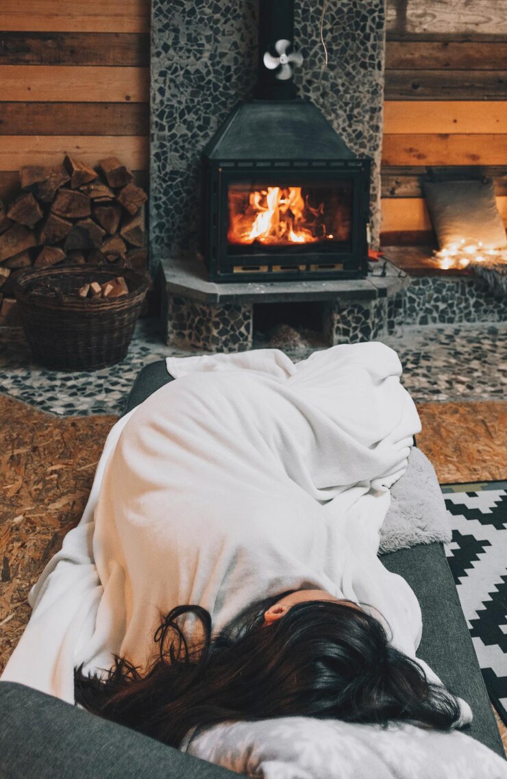 Photo woman sleeping on couch by fireplace in cozy warm cabin