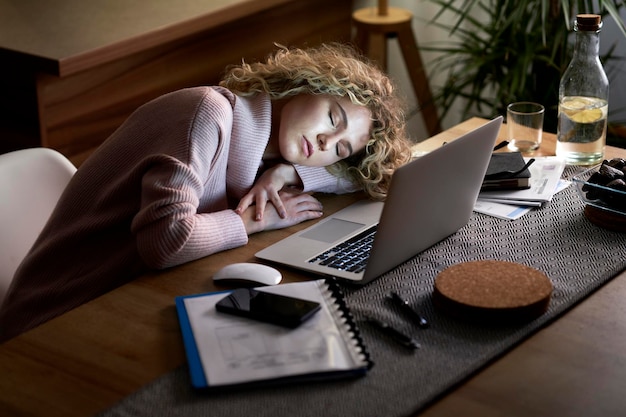 Woman sleeping on the desk in front of the laptop