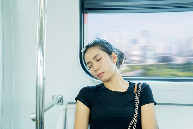 写真 窓に向かって列車に座って寝ている女性