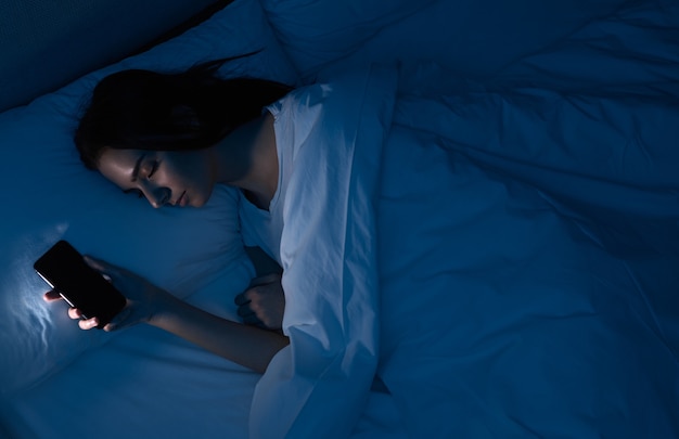 Woman sleeping with smartphone in bed