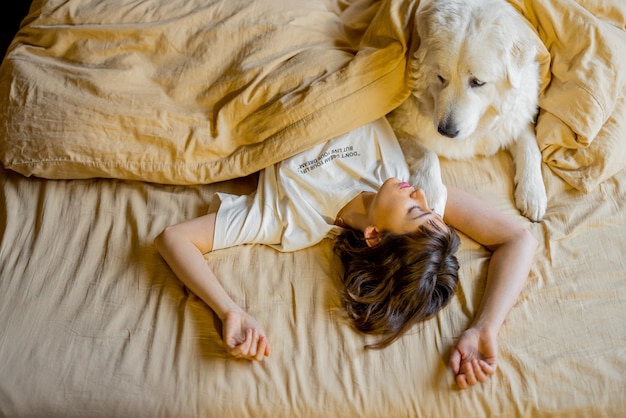 여자는 침대에서 그녀의 귀여운 강아지와 잔다